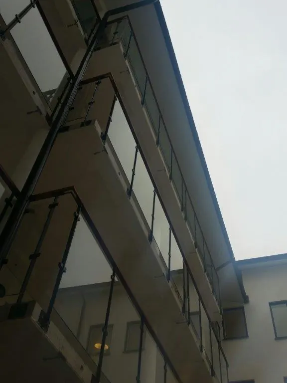 Balkongräcken i glas med svarta stålstolpar sedda underifrån